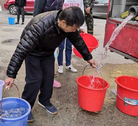 居民在消防车上接水,靠人力一桶一桶提上楼。