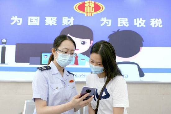 深圳市龙岗区税务局税务干部为纳税人讲解“全区通办”清单,详细介绍相关业务的办理流程。